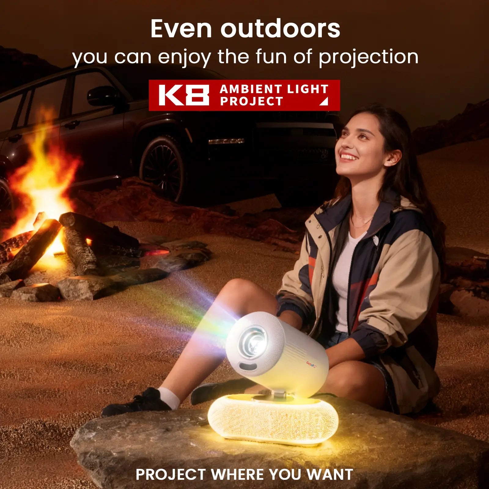 A woman enjoying an outdoor movie night with the portable Geitepor K8 projector, set up next to a campfire under the stars, showcasing its versatility.