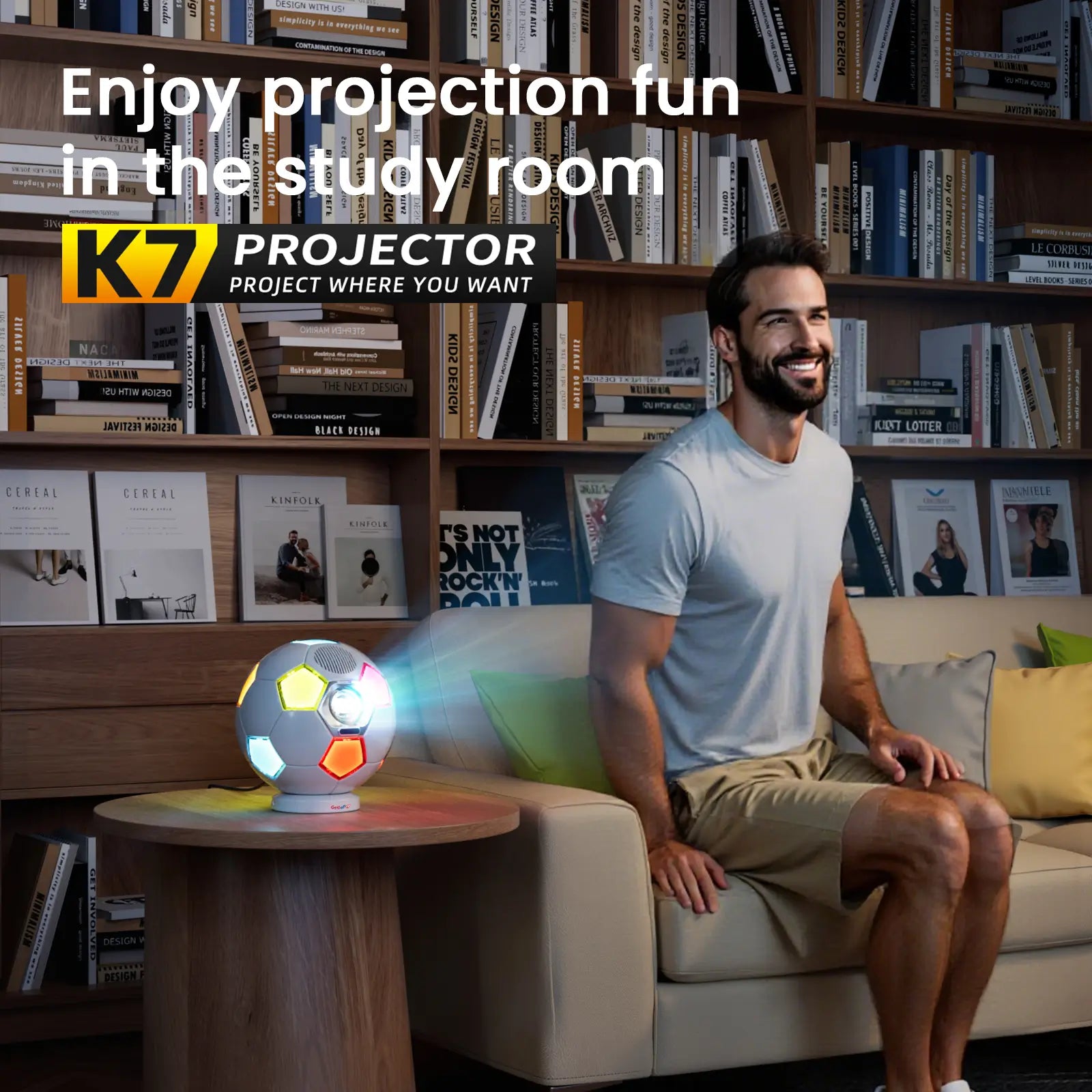 A man smiling while enjoying a movie in his study, projected by the K7 projector which is glowing with colorful ambient light.
